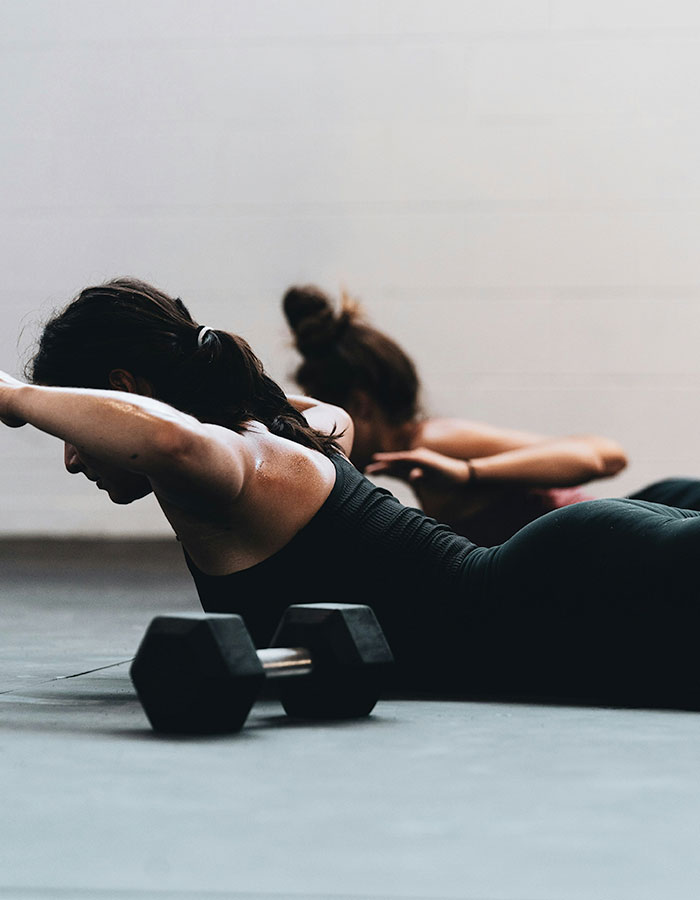 A person lying on their front on a yoga mat with their arms raised at their sides