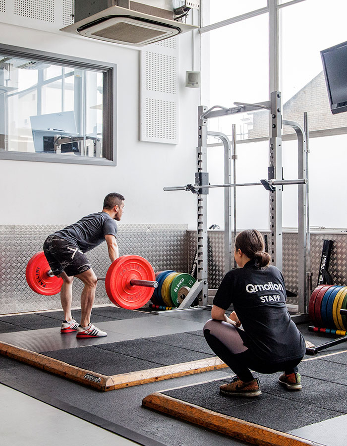 A student performing a lift with the help of QMOTION staff