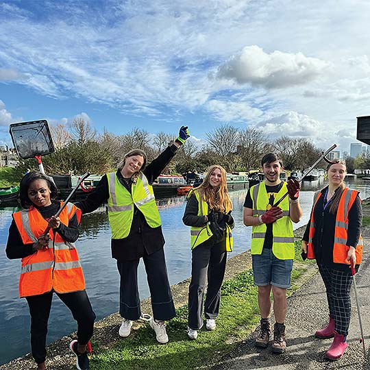 Five students wearing hi vis jackets, litter picking along the Thames